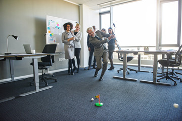 Fototapeta na wymiar Office colleagues enjoying a light hearted game of mini golf