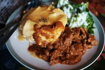 Thai Food Panaeng Curry with Pork and omelet on cooked rice in white plate