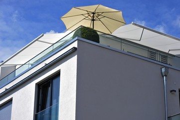 Dachterrasse mit automatischen Markisen und Sonnenschirm auf modernem Wohnhaus