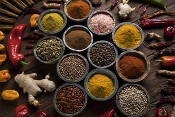 A selection of various colorful spices on a wooden table in bowls