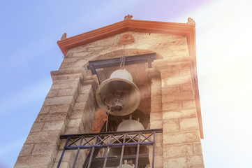 Church bell tower against blue sky with sun flare in Greece island Rhodes