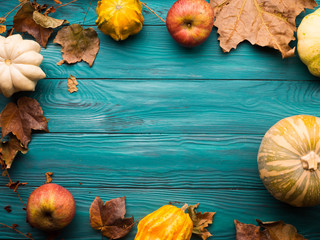 Moody green autumn background with pumpkin, apples, yellow leaves. Fall still life flat lay. Copy space frame