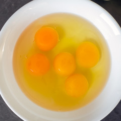 Fresh eggs in a white bowl. Concept of organic products. Farm. Broken eggs with bright yolks.