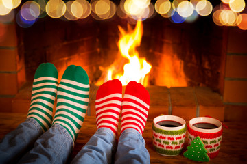Couple in Christmas socks near fireplace