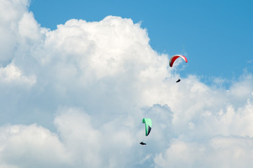 Two paragliders flying in the blue sky against the background of clouds. Paragliding in the sky on a sunny day.