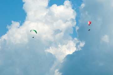 Two paragliders flying in the blue sky against the background of clouds. Paragliding in the sky on a sunny day.