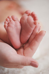 mother holds little foot of newborn baby