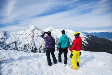 Rear view of young people enjoying in snowy winter on the top of the mountain with amazing background look.