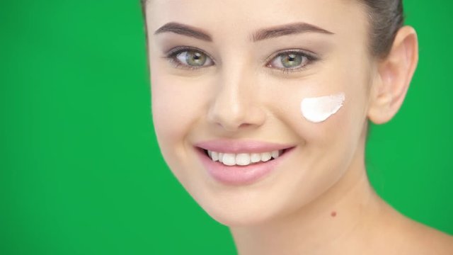 Beautiful girl applies cosmetics cream on the face