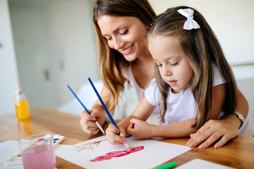 Little girl painting with her mother at home