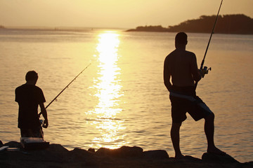 Father and son catching fish at sundown