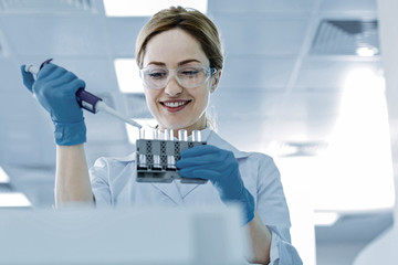 Medical research. Positive delighted intelligent woman holding test tubes and doing an analysis...