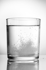 Aspirin, vitamins, fizzing in a glass of water.