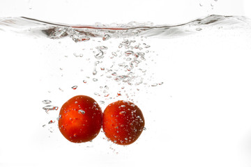 Red tomatoes falling into water