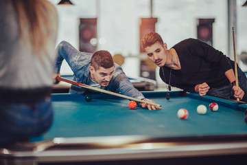 Fototapeta premium Group of young friends playing billiard in cafe