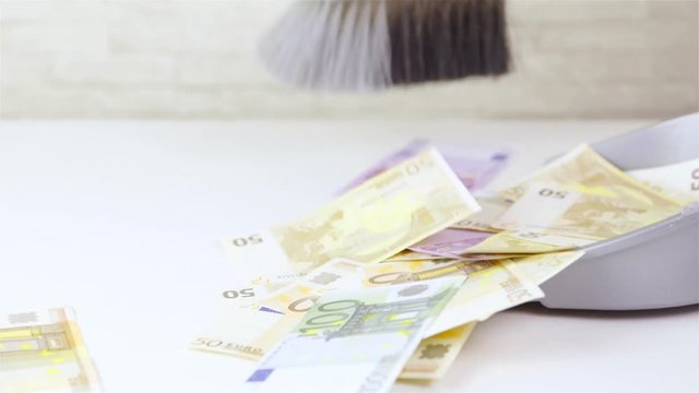Cleaning up money with dustpan and brush 4K
