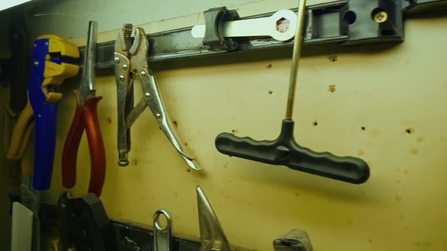 Slow motion shot of different tools hanging on magnetic plate. Tools on home workshop wooden desk at wall.