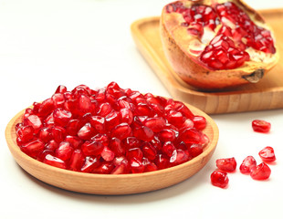 pomegranate seeds in wooden plate isolated on white background