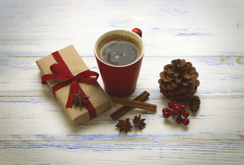 Packed gift, a cup of coffee with a heart, cinnamon, star anise, viburnum, cones