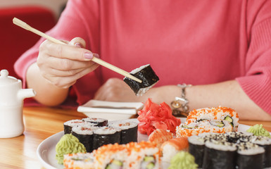 The best sushi rolls, Japanese cuisine. Various delicious sushi rolls. The hand is dipped in soy sauce,