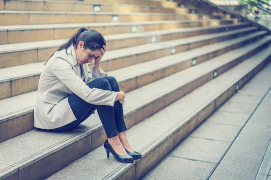 Business woman stressed from work while sitting outdoors on the stairs, concept work life balance, burn out syndrome, press from colleagues.
