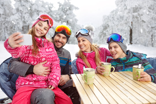 Girl with parents and brother making selfie at winter holiday