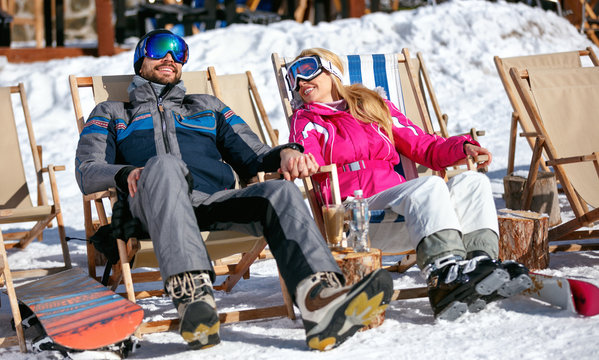 Couple at mountains in winter laughing and relax in sunbed