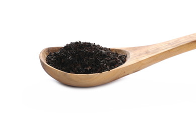 Black tea leaves in wooden spoon isolated on white background