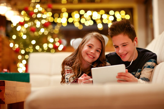 boy and girl with headphones lying and using a tablet for Christmas.