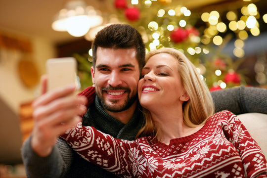 romantic couple taking selfie picture with smartphone at home.