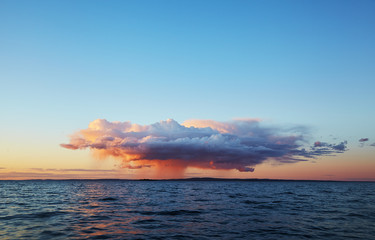 Lonely rain cloud against the clear sky at sunset
