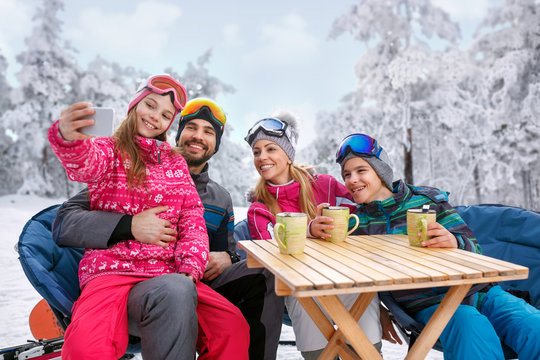 young girl with family enjoying in winter vacation on snow and making selfie