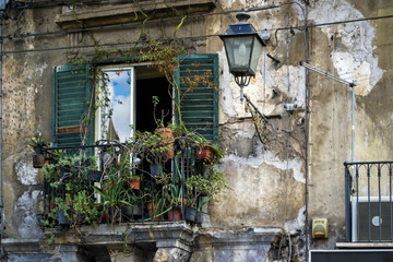 Fototapeta na wymiar a balcony with flowers and a lantern on an old house