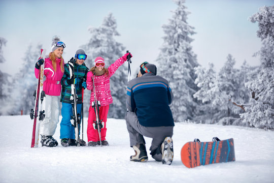 father taking picture of family standing in snow on the mountain