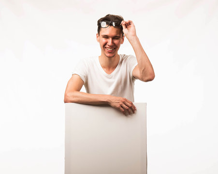 Young happy man portrait of a confident businessman showing presentation, pointing paper placard gray background. Ideal for banners, registration forms, presentation, landings, presenting concept.