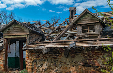 Fototapeta na wymiar An big old abandoned ruined wooden building. Broken doorway and andattic