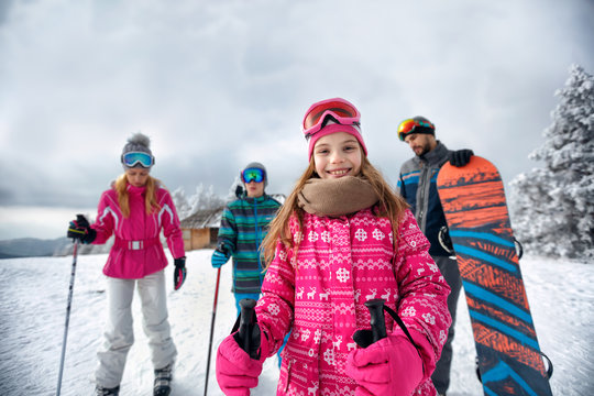 smiling girl with family on ski slope on vacation in mountain