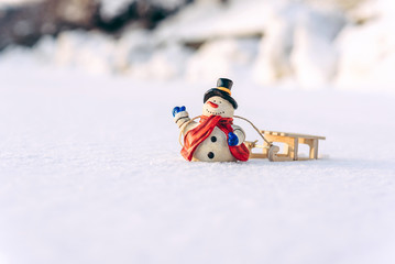 Naklejka premium Closeup christmas decorations snowman and sled on the snow.