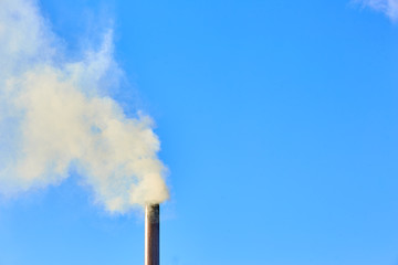 Smoke comes from the chimney of the house. The pipe on the roof. Chimney. Country house. The house with a chimney. Smoke in the blue sky. Smoke stacks and sky clouds