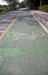 The white bicycle painting on the green bike lane. it is a division of a road marked off with painted lines, for use by cyclists.