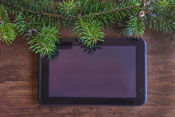 touch pad and fir branch frame on wooden background top view