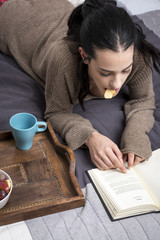 Fototapeta na wymiar Pensive model with snack reading book
