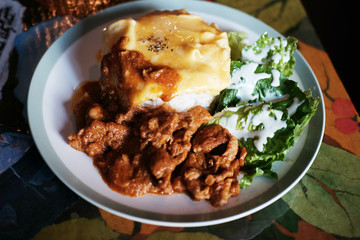 Thai Food Panaeng Curry with Pork and omelet on cooked rice in white plate