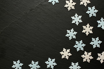 White and blue sugar snowflakes on black background with space for your message