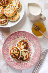 Cottage cheese pancakes, homemade syrniki with honey and sour cream.