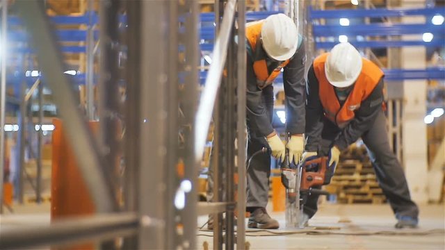 Slow Motion Workers Fix with Drills Metal Racks in Warehouse