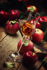 Strong golden alcoholic drink from apples, vintage wooden background, selective focus