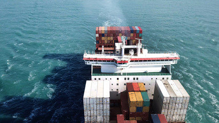 Huge large mega ULCV container ship sails on open water fully loaded with containers and cargo - aerial view