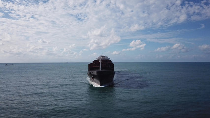 Huge large mega ULCV container ship sails on open water fully loaded with containers and cargo - aerial view