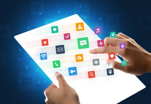 Hands touching a glass-like tablet with colorful icons